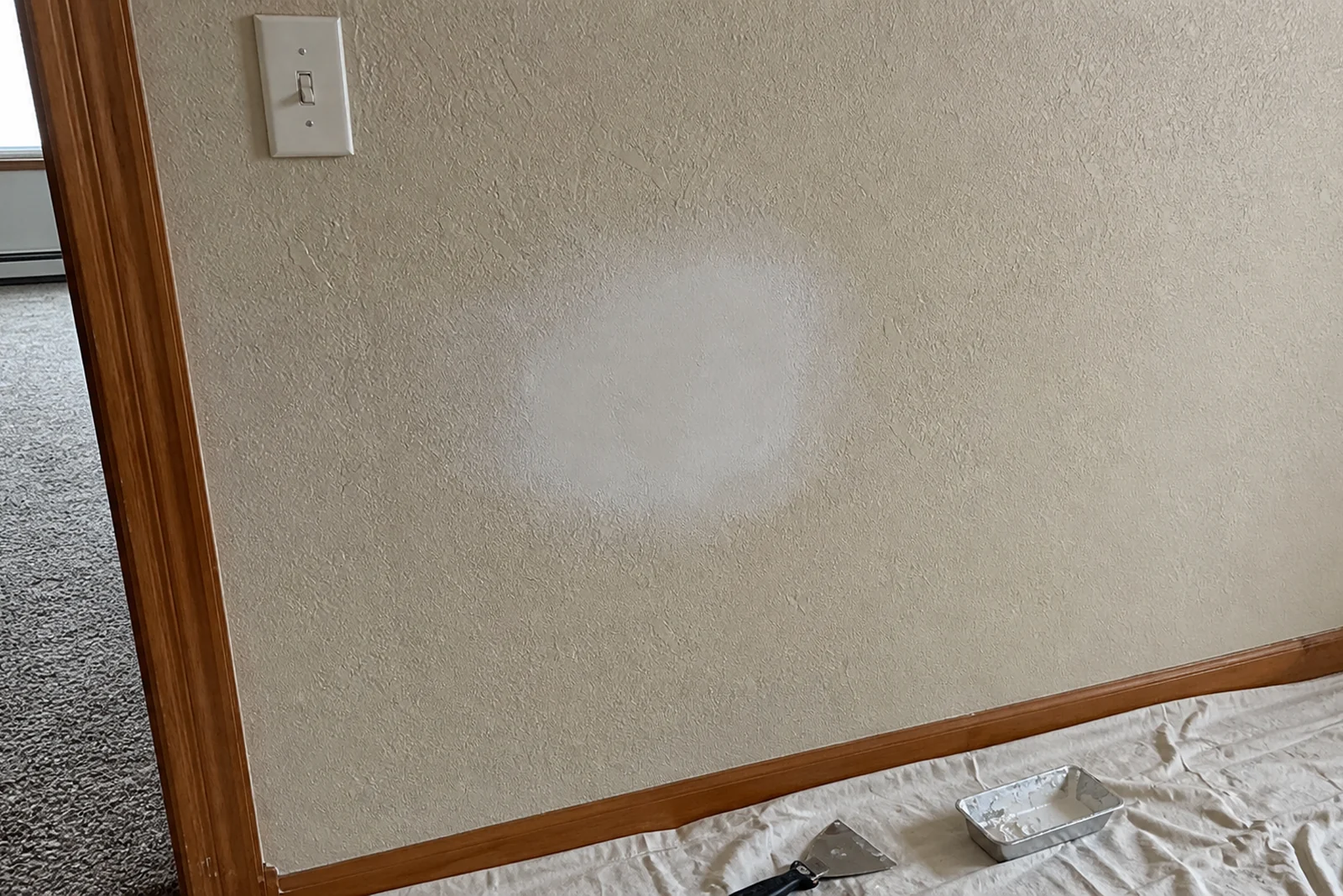 Clean patched drywall repair on textured Rexburg Idaho wall with drop cloth and drywall tools